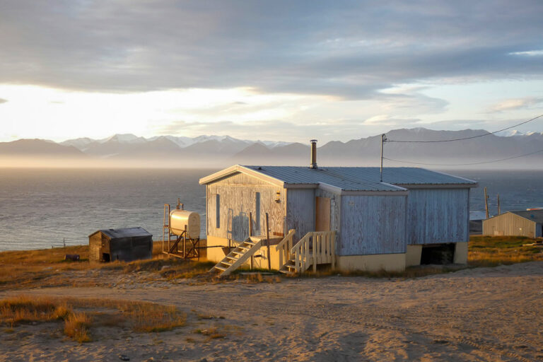 Ein Holzhaus in der Kanadischen Artkis mit Blick auf das Meer
